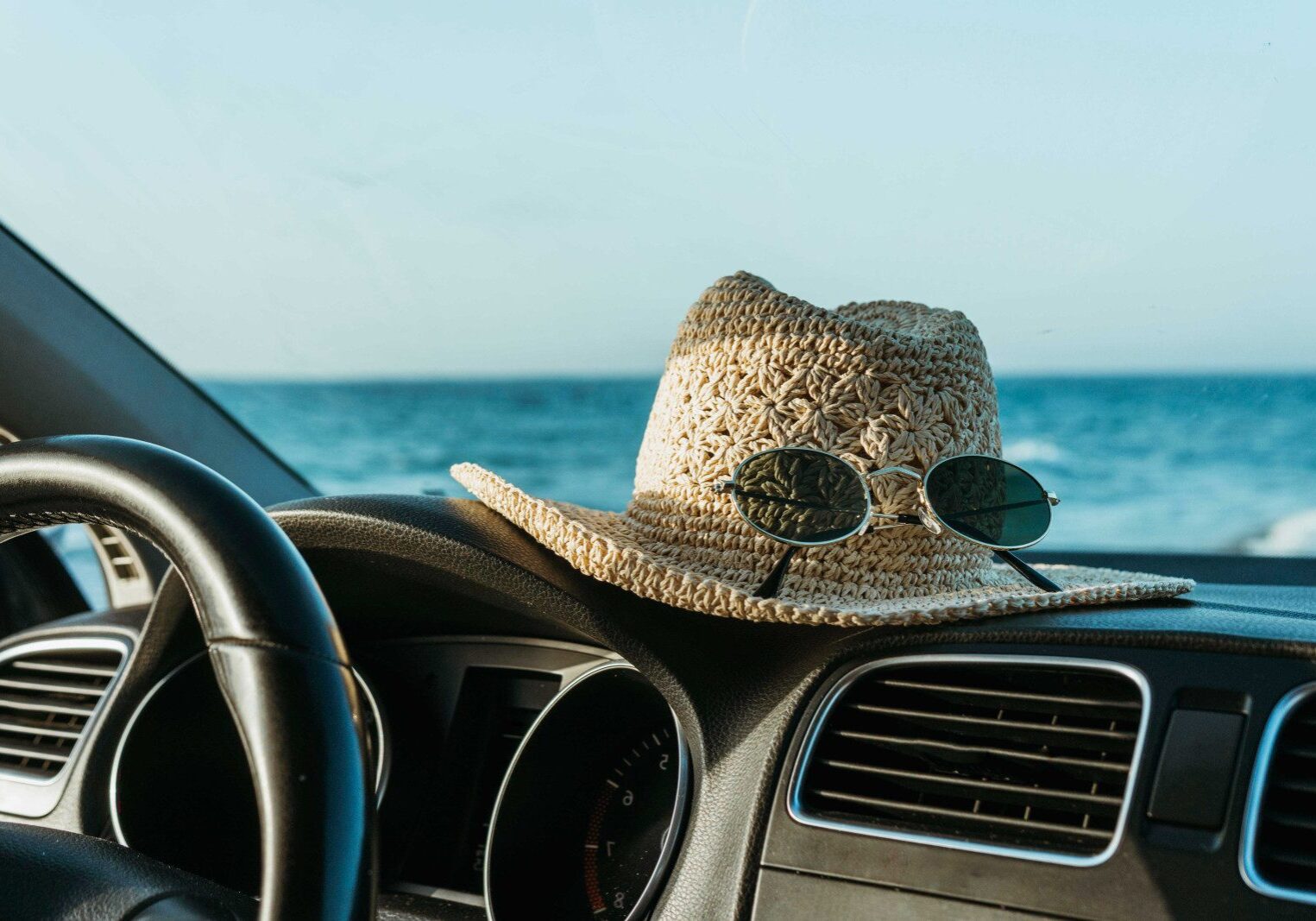 hat and sunglasses on a car dashboard in a tropical setting